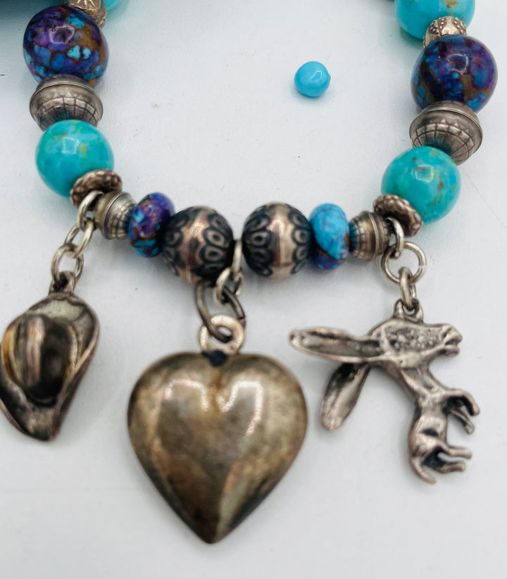 Stretch bracelet featuring Kingman turquoise, purple Mojave turquoise, sterling silver beads, and vintage sterling silver charms. Available only from Rockstar Cowgirl online or in store in Cody, Wyoming.