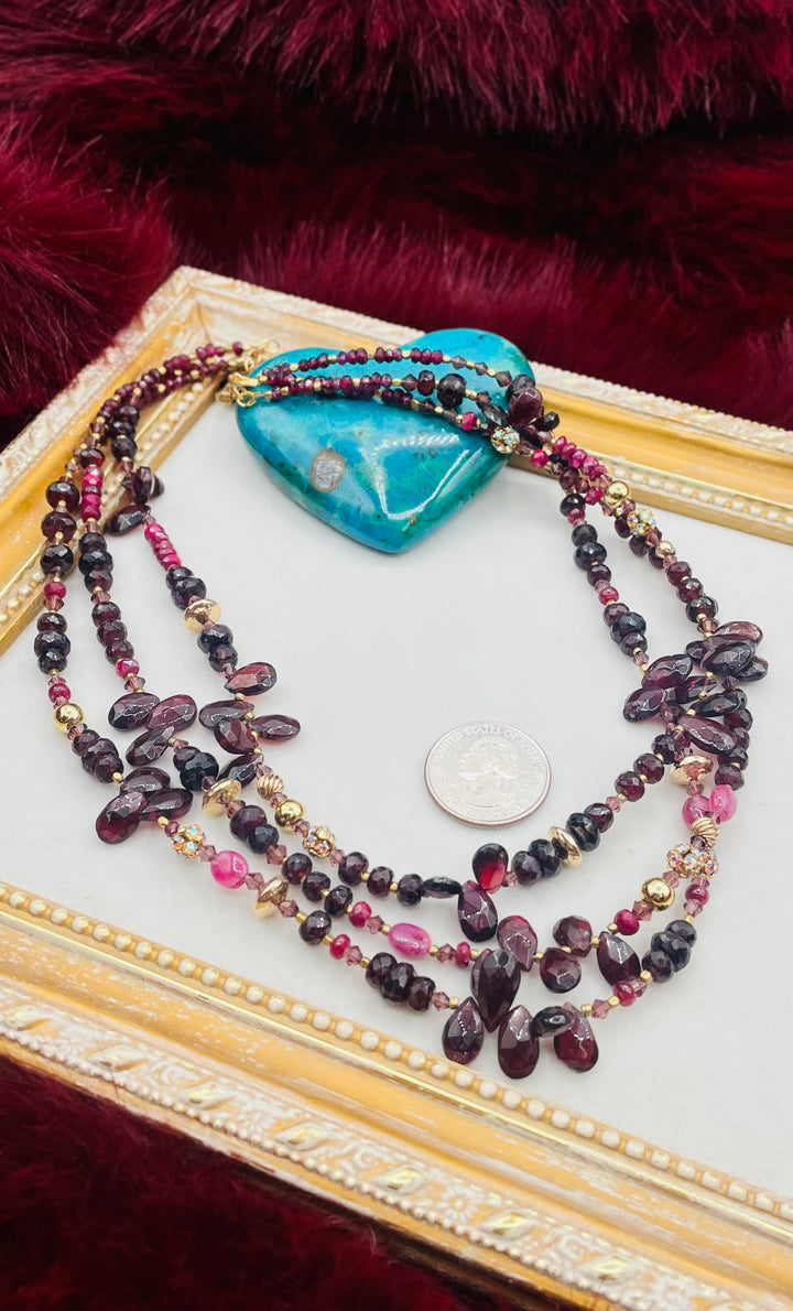 Nested 3 strand necklace featuring garnets, rubies, purple crystals, 14K gold accents, and African brass spacers. U.S. quarter for size reference. Available only from Rockstar Cowgirl online or in store in Cody, Wyoming.