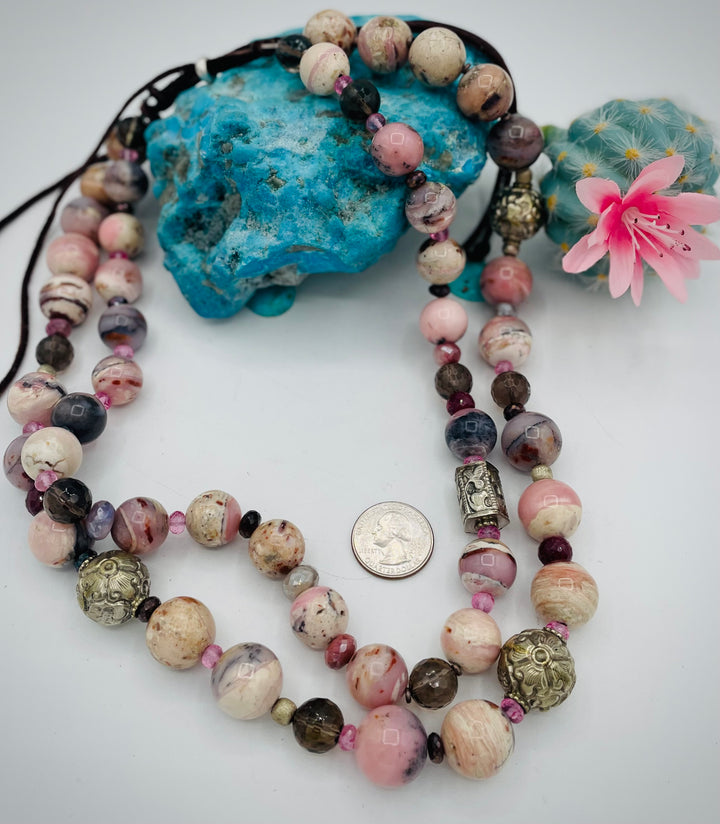 Beaded necklace featuring pink opal, repousse beads, smokey quartz, ruby, pink topaz, sterling silver beads, moonstone, and finished with deer lace in the back. U.S. quarter for size reference. Available only from Rockstar Cowgirl online or in store in Cody, Wyoming.