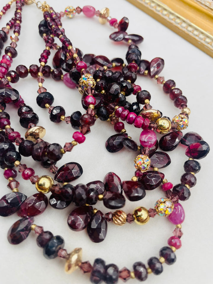 Nested 3 strand necklace featuring garnets, rubies, purple crystals, 14K gold accents, and African brass spacers. Available only from Rockstar Cowgirl online or in store in Cody, Wyoming.