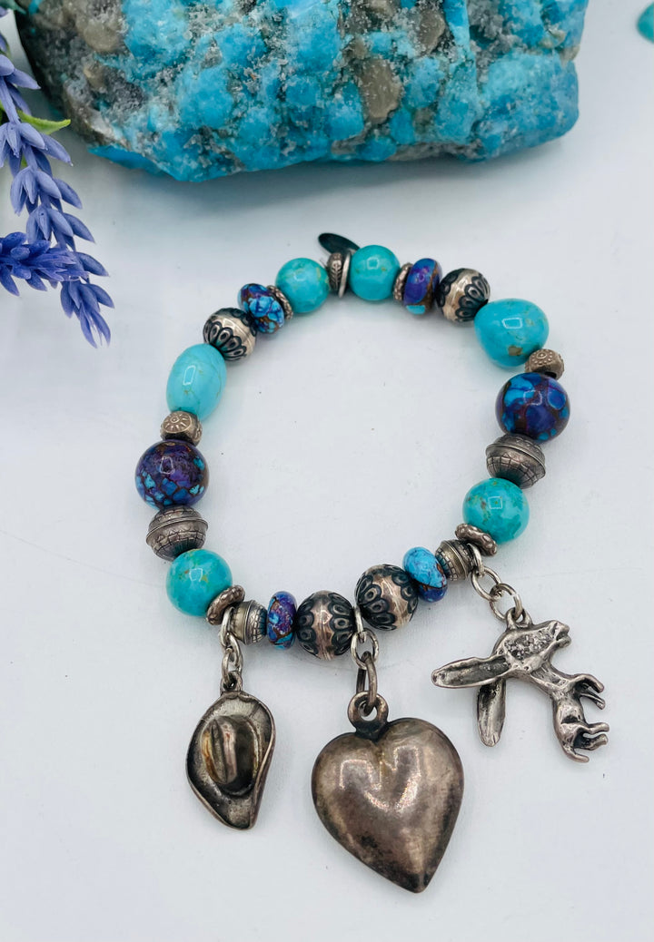 Stretch bracelet featuring Kingman turquoise, purple Mojave turquoise, sterling silver beads, and vintage sterling silver charms. Available only from Rockstar Cowgirl online or in store in Cody, Wyoming.