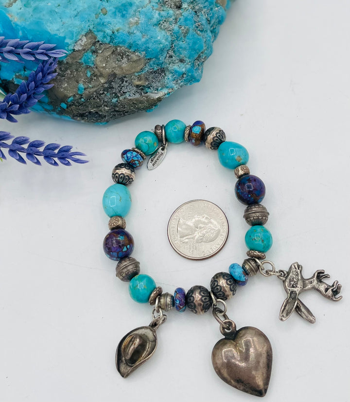 Stretch bracelet featuring Kingman turquoise, purple Mojave turquoise, sterling silver beads, and vintage sterling silver charms. U.S. quarter for size reference. Available only from Rockstar Cowgirl online or in store in Cody, Wyoming.