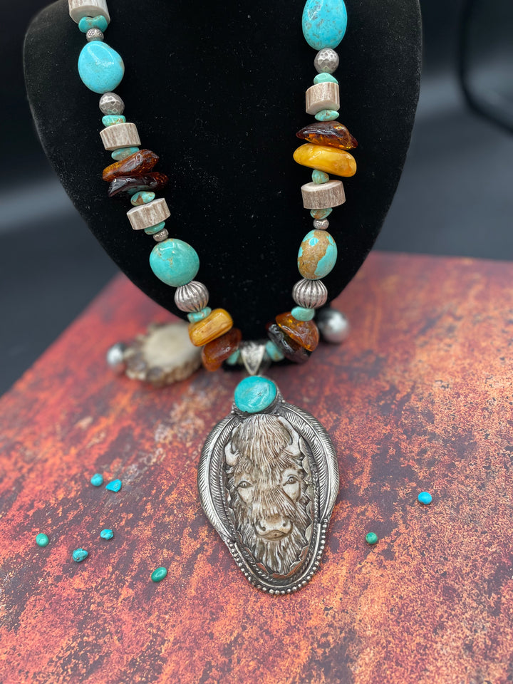 A decadent Bison necklace featuring large chips of Baltic amber, turquoise, antler, and Hill tribe sterling silver beads. The bison pendent is hand carved bone set in a silver pendent with a turquoise accent. Available only with Rockstar Cowgirl online or in store in Cody, Wyoming.