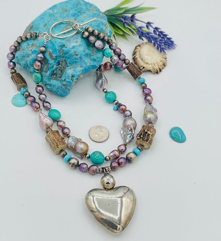 Fruity’s necklace features purple Edison pearls, Kingman turquoise nuggets and rondells, vintage sterling silver beads, deer antler, flameball pearls, and a sterling silver puffy heart pendant. U.S. quarter for size reference. Available only from Rockstar Cowgirl online or in store in Cody, Wyoming.