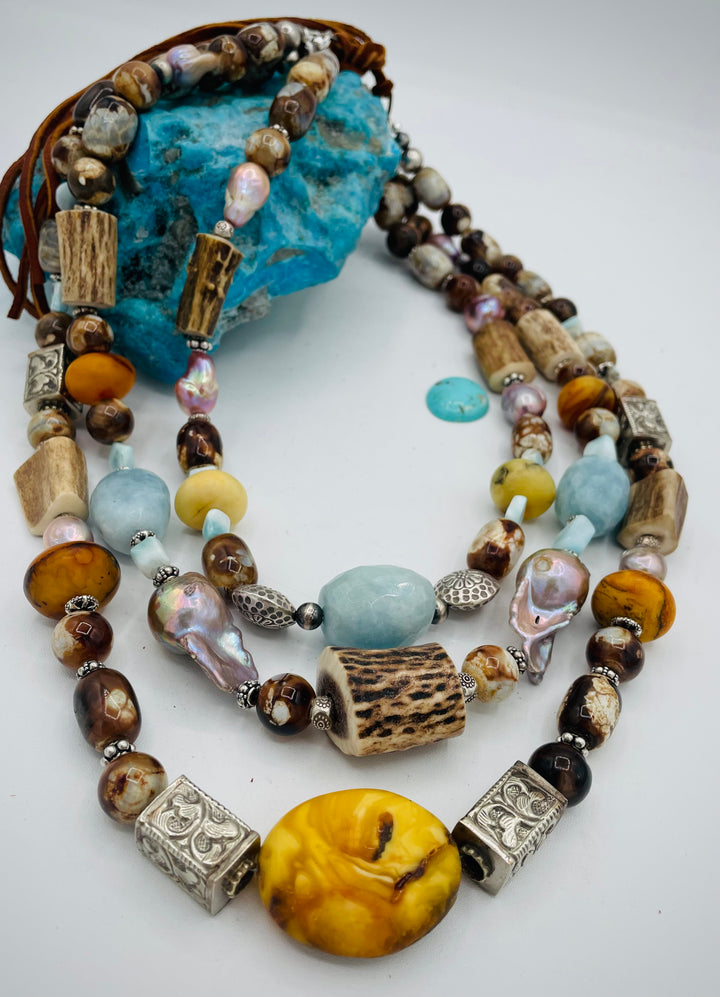 Chunky 3 strand beaded necklace featuring Baltic amber, baroque natural luster pearls, deer antler, larimar, aquamarine, wood opal, silver repousse beads, and sterling silver. Available only from Rockstar Cowgirl online or in store in  Cody, Wyoming.