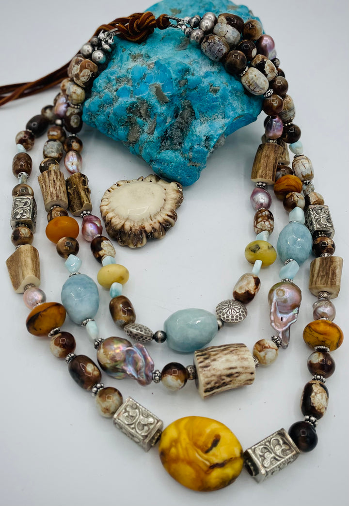 Chunky 3 strand beaded necklace featuring Baltic amber, baroque natural luster pearls, deer antler, larimar, aquamarine, wood opal, silver repousse beads, and sterling silver. Available only from Rockstar Cowgirl online or in store in  Cody, Wyoming.