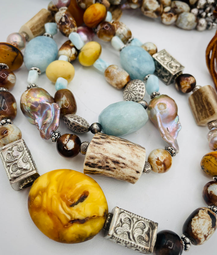 Chunky 3 strand beaded necklace featuring Baltic amber, baroque natural luster pearls, deer antler, larimar, aquamarine, wood opal, silver repousse beads, and sterling silver. Available only from Rockstar Cowgirl online or in store in  Cody, Wyoming.