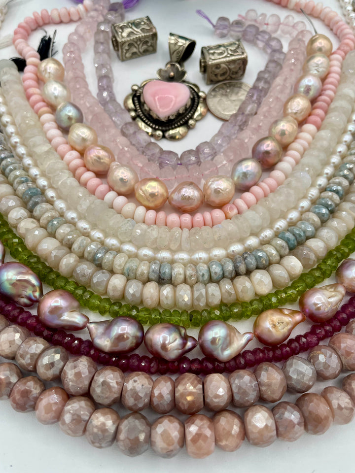 Bead box featuring strands of silverite, ruby, pearls, peridot, moonstone, opal, rose quartz, pink amethyst, with Repousse beads, and a pink conch shell pendant. U.S. quarter for size reference. Available only from Rockstar Cowgirl online or in store in Cody,Wyoming.