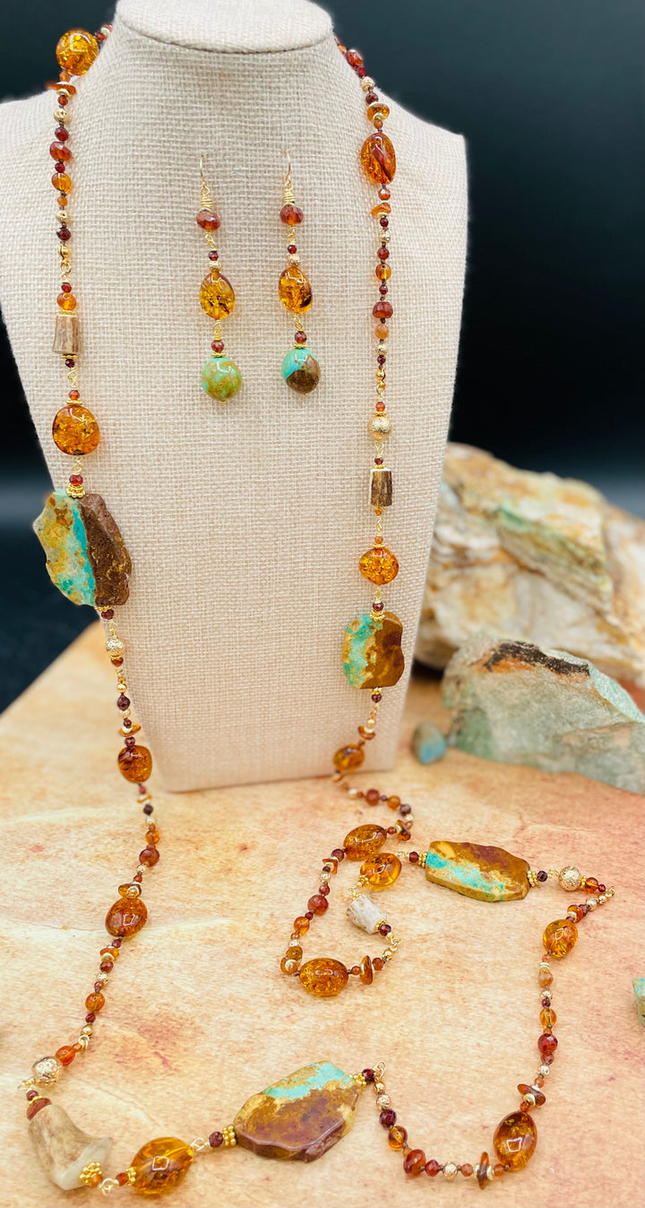 A Baltic amber treasure necklace featuring Kingman turquoise, garnets, and deer antler sprinkled throughout this silk knotted and wire wrapped set with matching earrings. Available only from Rockstar Cowgirl online and in store in Cody, Wyoming.