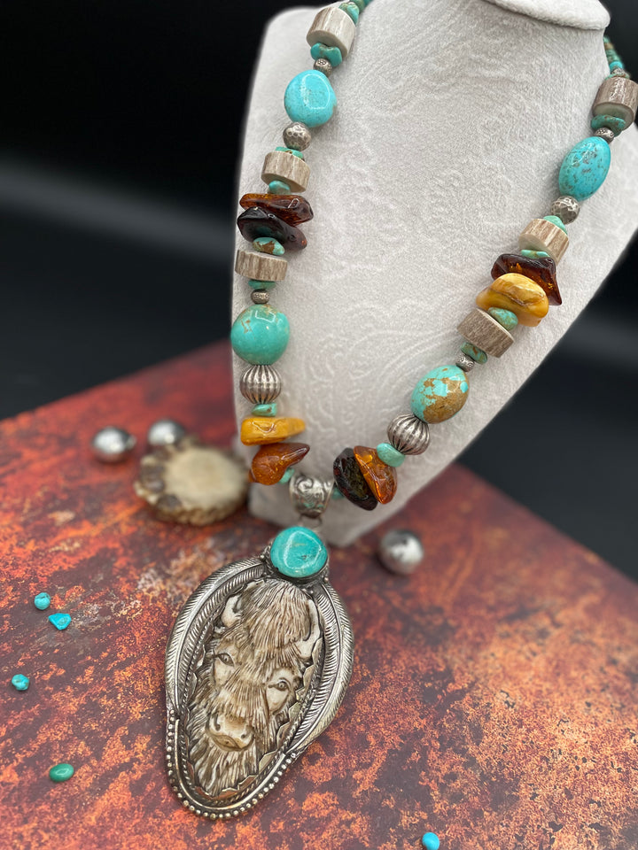 A bold necklace featuring a bison and turquoise pendent flanked with Baltic amber, turquoise, polished antler beads and sterling silver. A bold one of a kind piece from Rockstar Cowgirl.