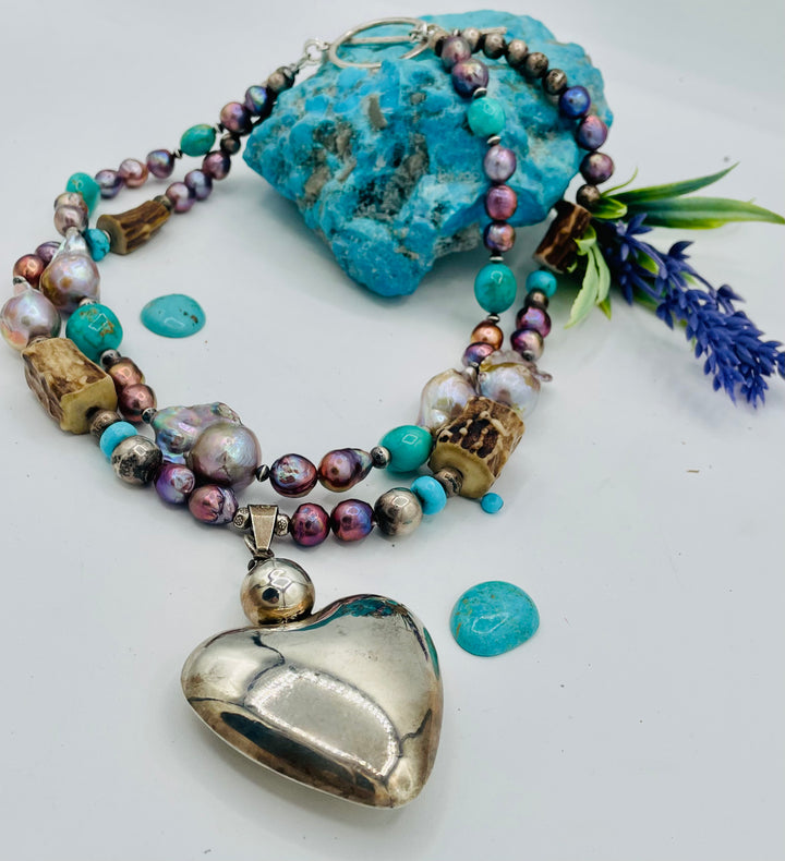 Fruity’s necklace features purple Edison pearls, Kingman turquoise nuggets and rondells, vintage sterling silver beads, deer antler, flameball pearls, and a sterling silver puffy heart pendant. Available only from Rockstar Cowgirl online or in store in Cody, Wyoming.