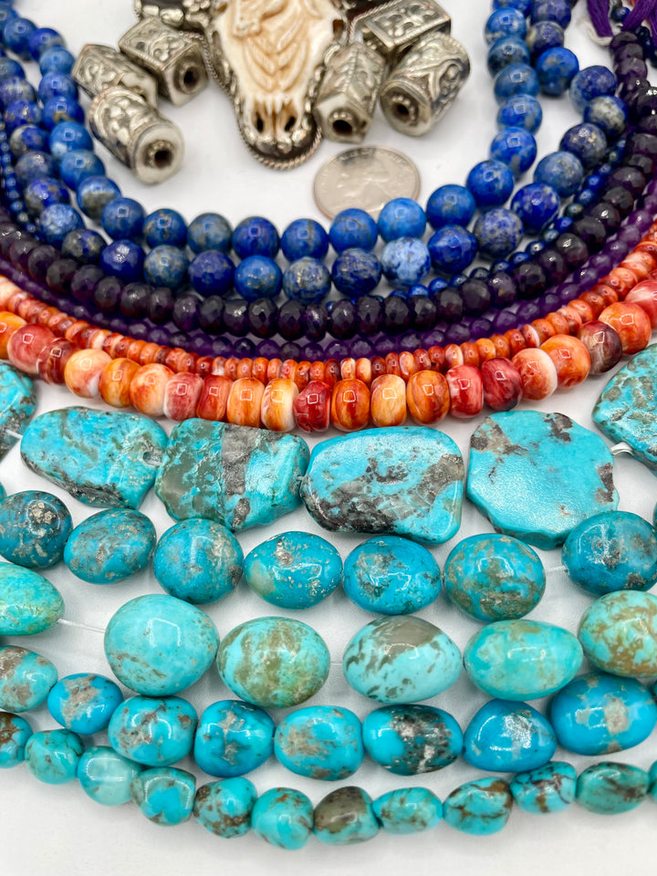 Bead box featuring strands of lapis, amethyst, spiney oyster, Kingman turquoise, Campitios turquoise, Repousse beads, with a bone and Bali silver steer pendent. U.S. quarter for size reference. Available only from Rockstar Cowgirl online or in store in Cody, Wyoming.