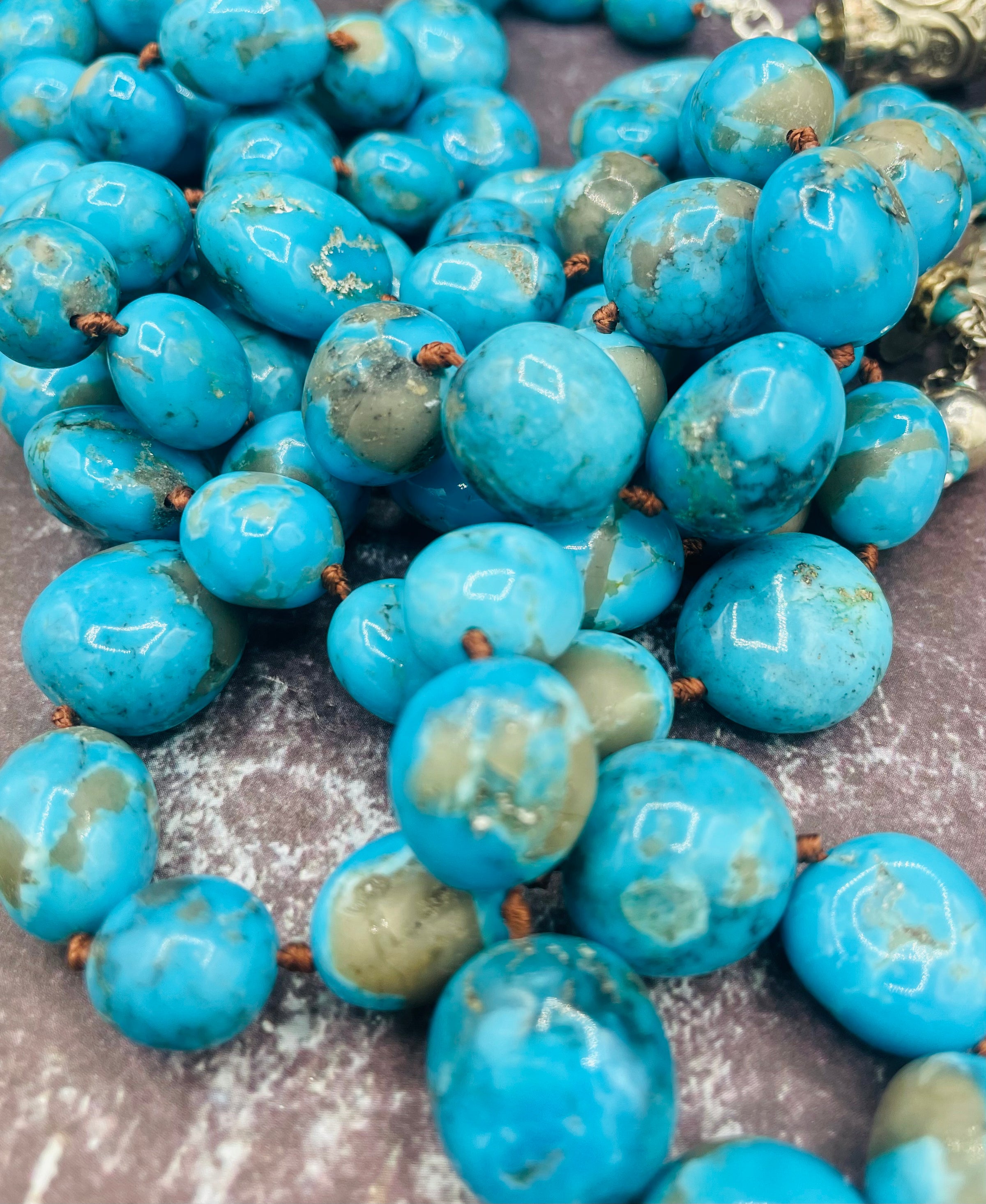 Ithaca peak turquoise silk knotted lariat with repousse beads and vintage sterling silver charms on the tails. Close up of the turquoise beads. Available only from Rockstar Cowgirl online or in store in Cody, Wyoming.
