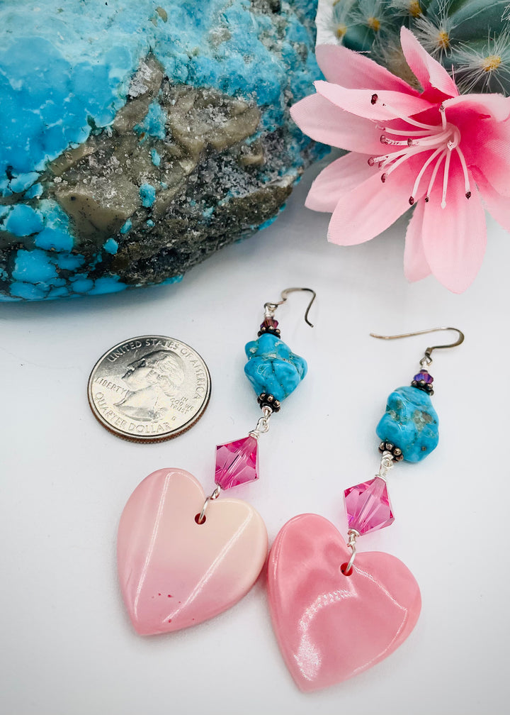 Handmade earrings featuring pink conch hearts, Swarovski crystals, and vintage Kingman turquoise. U.S. quarter for size reference. Available only from Rockstar Cowgirl online or in store in Cody, Wyoming.