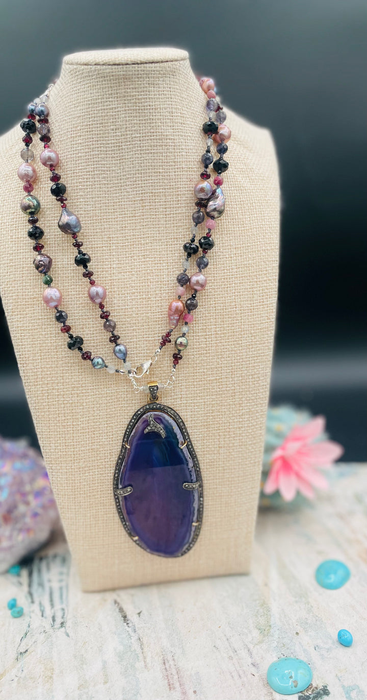 Silk knotted and wire wrapped treasure necklace featuring Peacock pearls, Edison natural luster pearls, spinel, garnets, iolite, labradorite, rainbow tourmaline, and a purple agate, sterling silver, and diamond pendent. Available only from Rockstar Cowgirl online or in store in Cody, Wyoming.