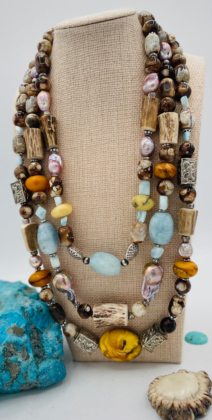 Chunky 3 strand beaded necklace featuring Baltic amber, baroque natural luster pearls, deer antler, larimar, aquamarine, wood opal, silver repousse beads, and sterling silver. Available only from Rockstar Cowgirl online or in store in  Cody, Wyoming.