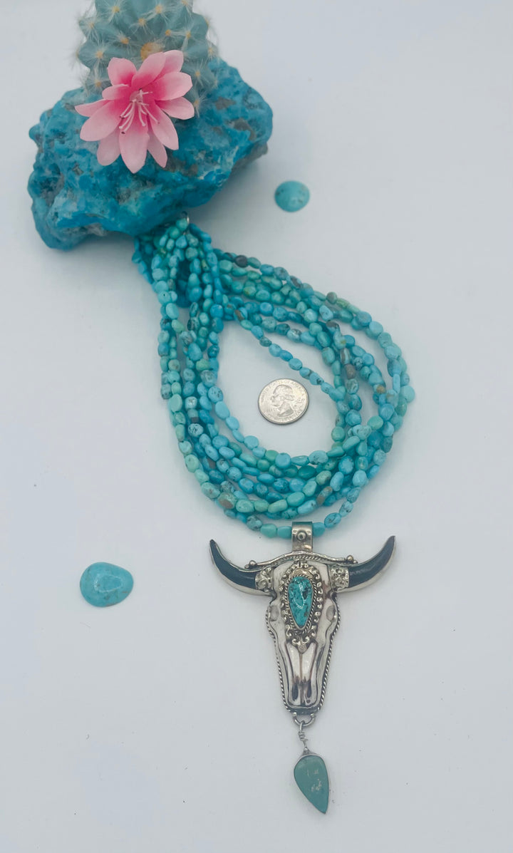 7 stranded beaded necklace featuring Sonoran turquoise nuggets, and a hand carved steer pendent with turquoise details. U.S. quarter for size reference. Available only from Rockstar Cowgirl online or in store in Cody, Wyoming.