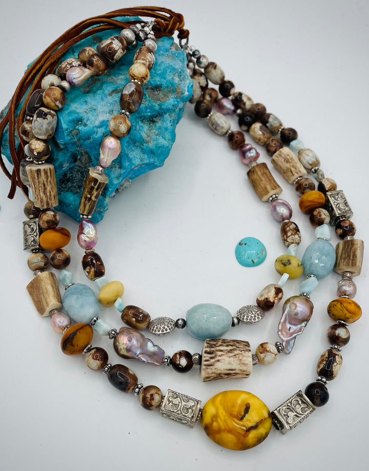 Chunky 3 strand beaded necklace featuring Baltic amber, baroque natural luster pearls, deer antler, larimar, aquamarine, wood opal, silver repousse beads, and sterling silver. Available only from Rockstar Cowgirl online or in store in  Cody, Wyoming.