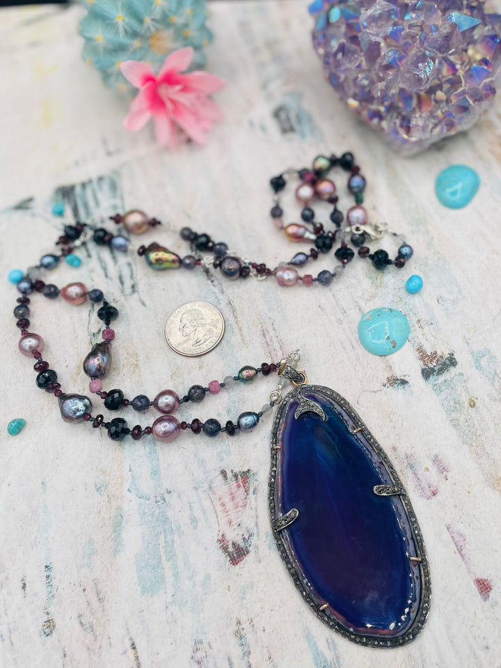 Silk knotted and wire wrapped treasure necklace featuring Peacock pearls, Edison natural luster pearls, spinel, garnets, iolite, labradorite, rainbow tourmaline, and a purple agate, sterling silver, and diamond pendent. Available only from Rockstar Cowgirl online or in store in Cody, Wyoming.