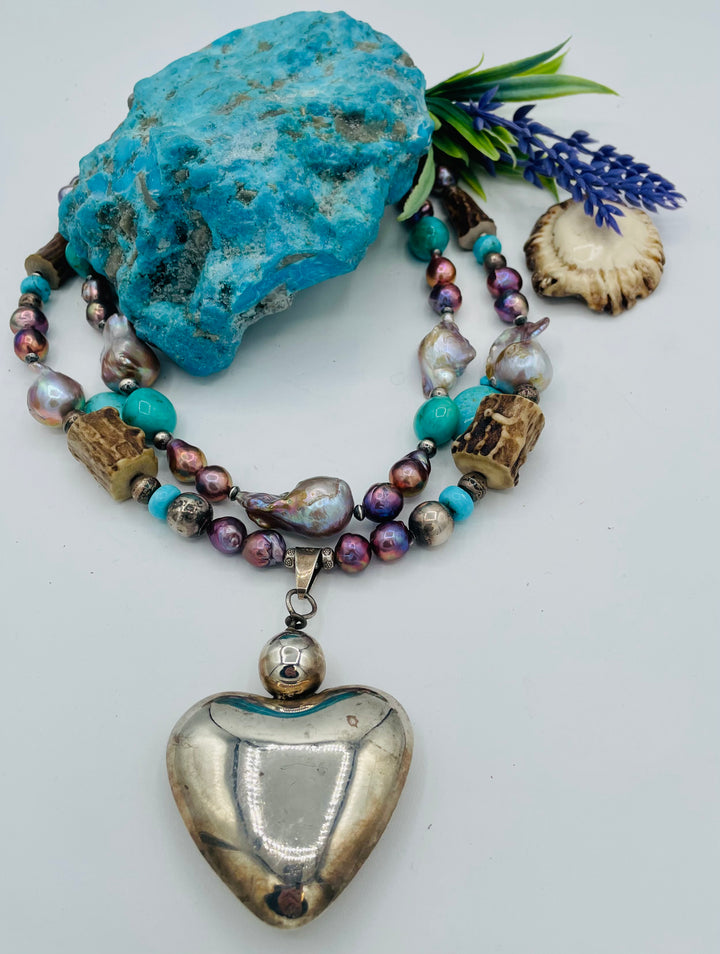 Fruity’s necklace features purple Edison pearls, Kingman turquoise nuggets and rondells, vintage sterling silver beads, deer antler, flameball pearls, and a sterling silver puffy heart pendant. Available only from Rockstar Cowgirl online or in store in Cody, Wyoming.