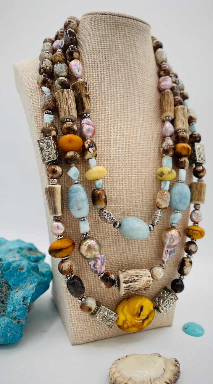 Chunky 3 strand beaded necklace featuring Baltic amber, baroque natural luster pearls, deer antler, larimar, aquamarine, wood opal, silver repousse beads, and sterling silver. Available only from Rockstar Cowgirl online or in store in  Cody, Wyoming.
