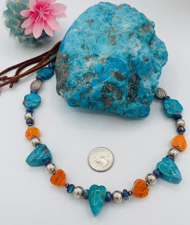 Adjustable beaded hatband featuring Kingman turquoise, purple Mojave turquoise, spiney oyster and turquoise hearts, sterling silver beads, and finished with deer lace in the back. U.S. quarter for size reference. Available only from Rockstar Cowgirl online or in store in Cody, Wyoming.