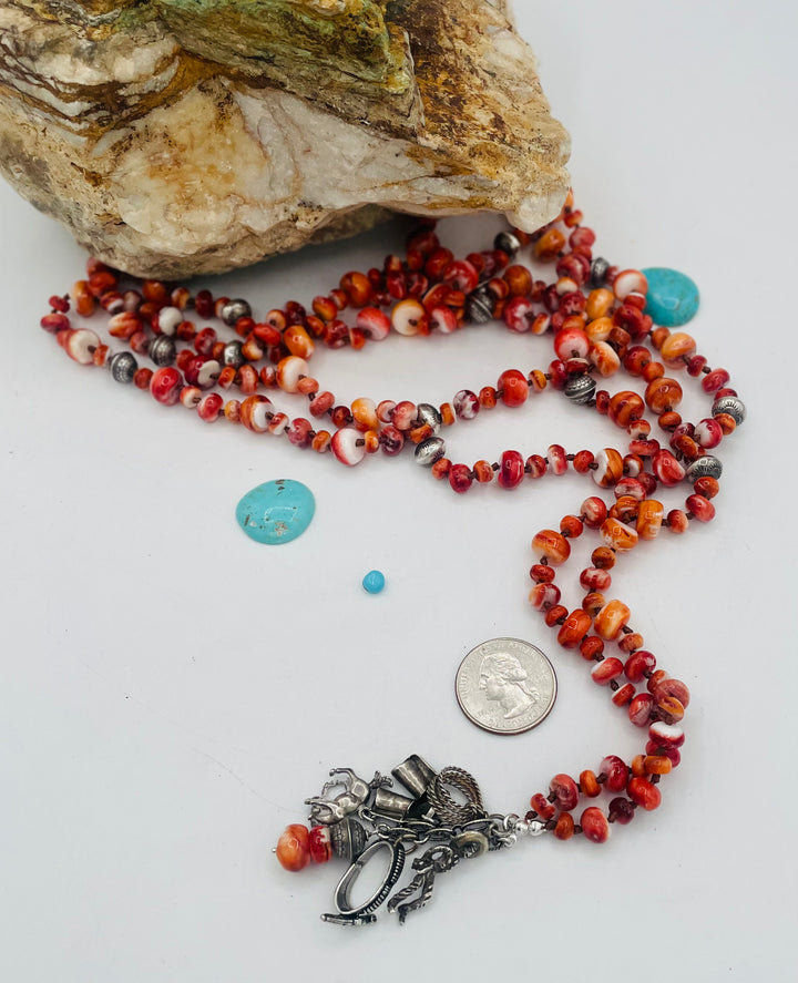 Silk knotted lariat necklace featuring spiney oyster, sterling silver stamped beads, and vintage sterling silver western charms. U.S. quarter for size reference. Available only from Rockstar Cowgirl online or in store in Cody, Wyoming.