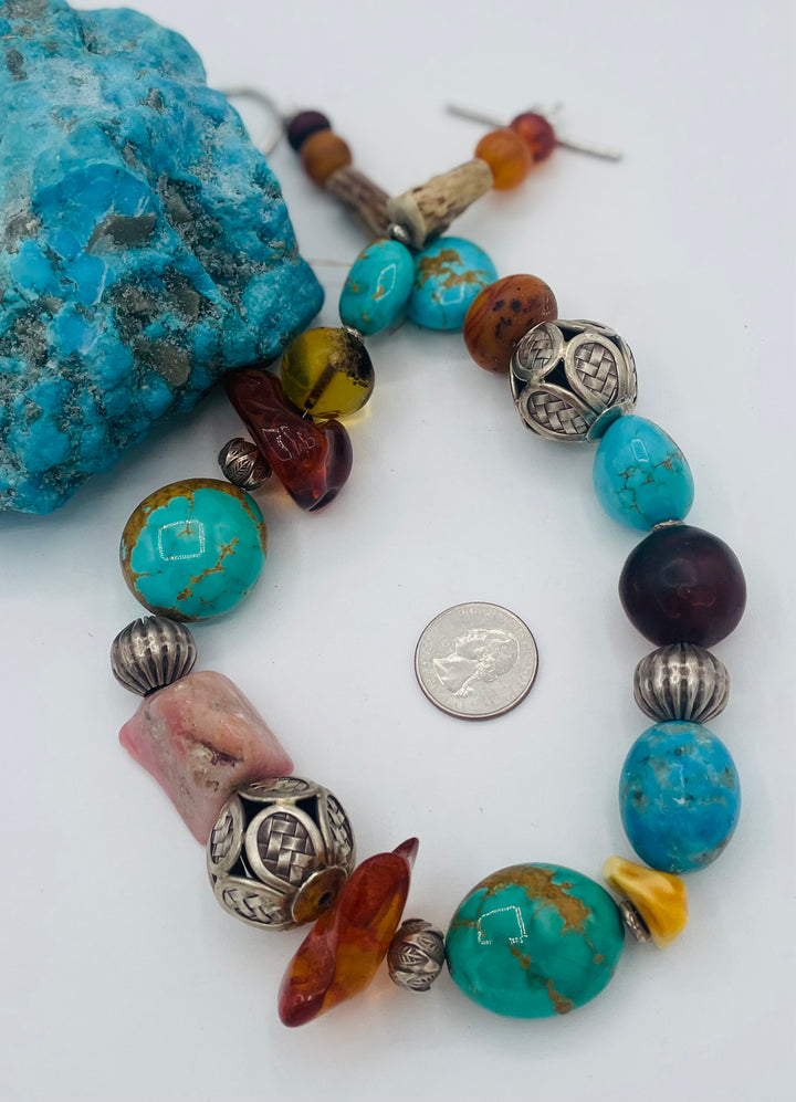Chunky beaded necklace featuring Kingman turquoise, Ithaca Peak turquoise, textured deer antler, Baltic amber, pink opal, and sterling silver beads. U.S. quarter for size reference. Available only from Rockstar Cowgirl online or in store in Cody, Wyoming.