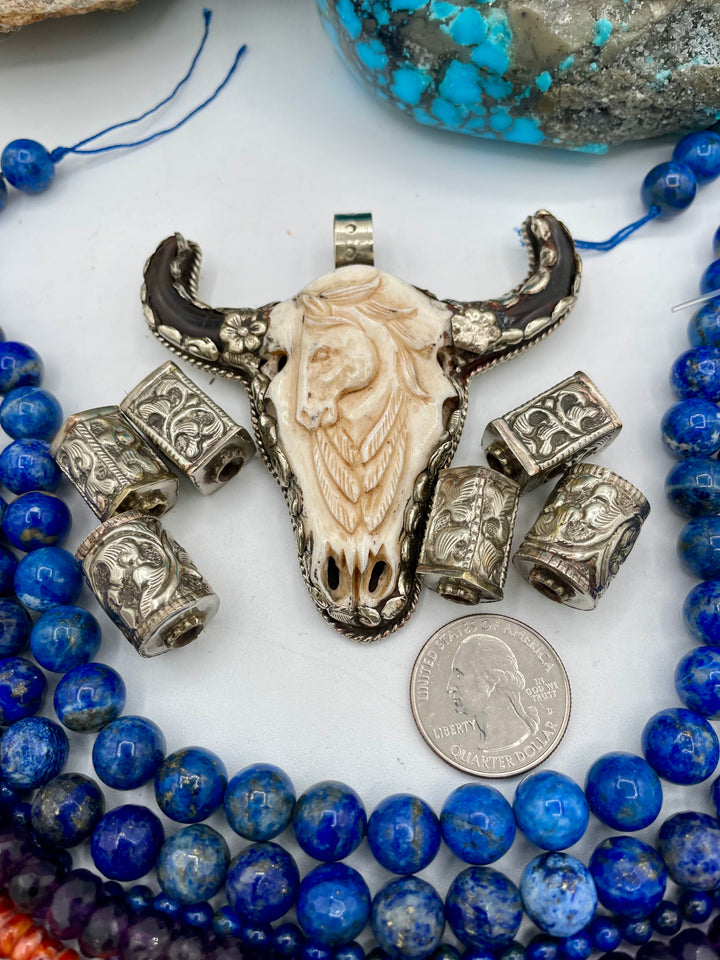 Bead box featuring strands of lapis, amethyst, spiney oyster, Kingman turquoise, Campitios turquoise, Repousse beads, with a bone and Bali silver steer pendent. U.S. quarter for size reference. Available only from Rockstar Cowgirl online or in store in Cody, Wyoming.