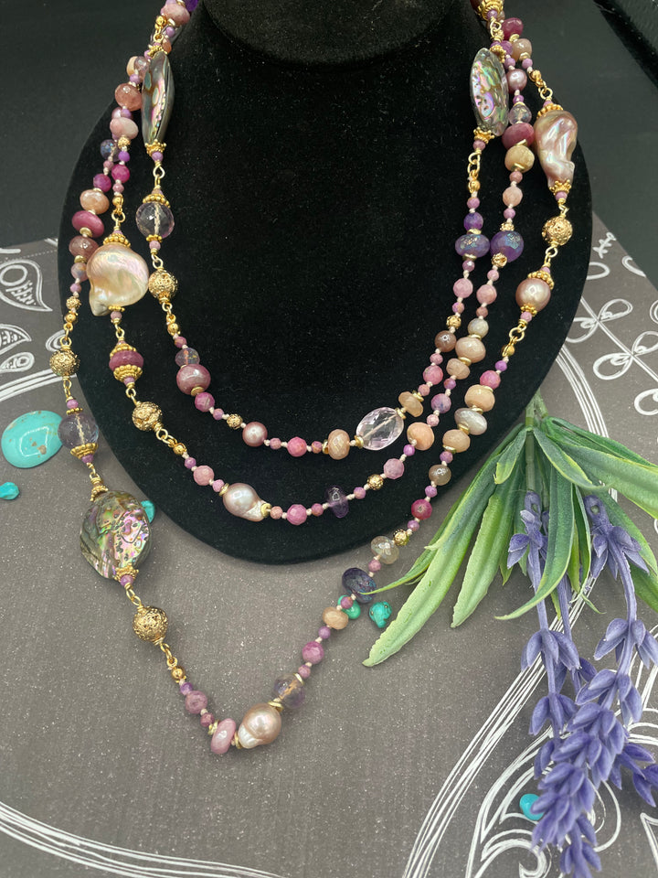 Silk knotted and wire wrapped treasure necklace featuring Rubies, pink amethyst, pink tourmaline, moonstone, abalone shells, and natural luster baroque pearls. Available only from Rockstar Cowgirl online or in store in Cody, Wyoming.