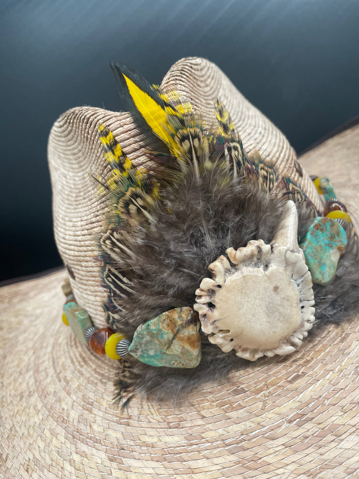 Close up of the feather burst with an antler crown flanked by Kingman turquoise slices with Baltic amber, sterling silver and yellow African glass. This hatband is adjustable with soft deer lace with an antler slide bead. One of a kind piece at Rockstar Cowgirl in Cody, Wy.
Cowgirl.