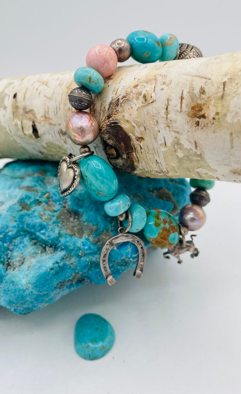 Beaded stretch bracelet featuring Kingman turquoise, royal beauty turquoise, pearls, rhodochrosite, purple turquoise, sterling silver beads and vintage sterling silver charms. Available only from Rockstar Cowgirl online or in store in Cody, Wyoming.
