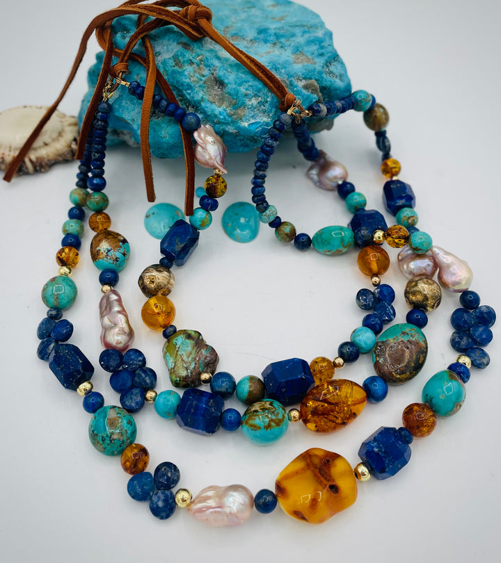 Beaded 3 strand necklace featuring lapis, Baltic amber, Kingman turquoise, 14K gold beads, natural luster pearls, and finished with deer lace in the back. Available only form Rockstar Cowgirl online or in store in Cody, Wyoming.