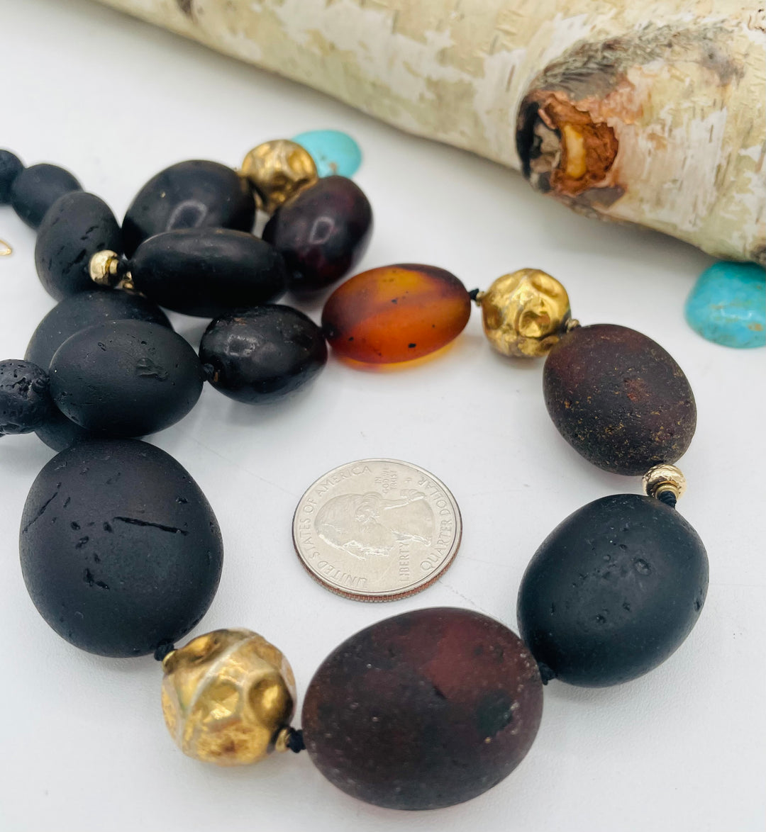 Silk knotted necklace featuring black Baltic amber nuggets, lava, and 14K gold beads. U.S. quarter for size reference. Available only from Rockstar Cowgirl online or in store in Cody, Wyoming.