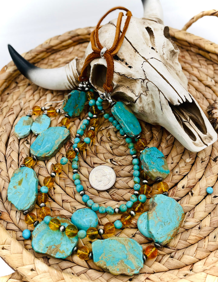 Beaded three strand necklace featuring Kingman turquoise, Baltic amber, sterling silver beads, and finished with deer lace and slide bead. Includes matching earrings. U.S. quarter for size reference. Available only from Rockstar Cowgirl online or in store in Cody, Wyoming.
