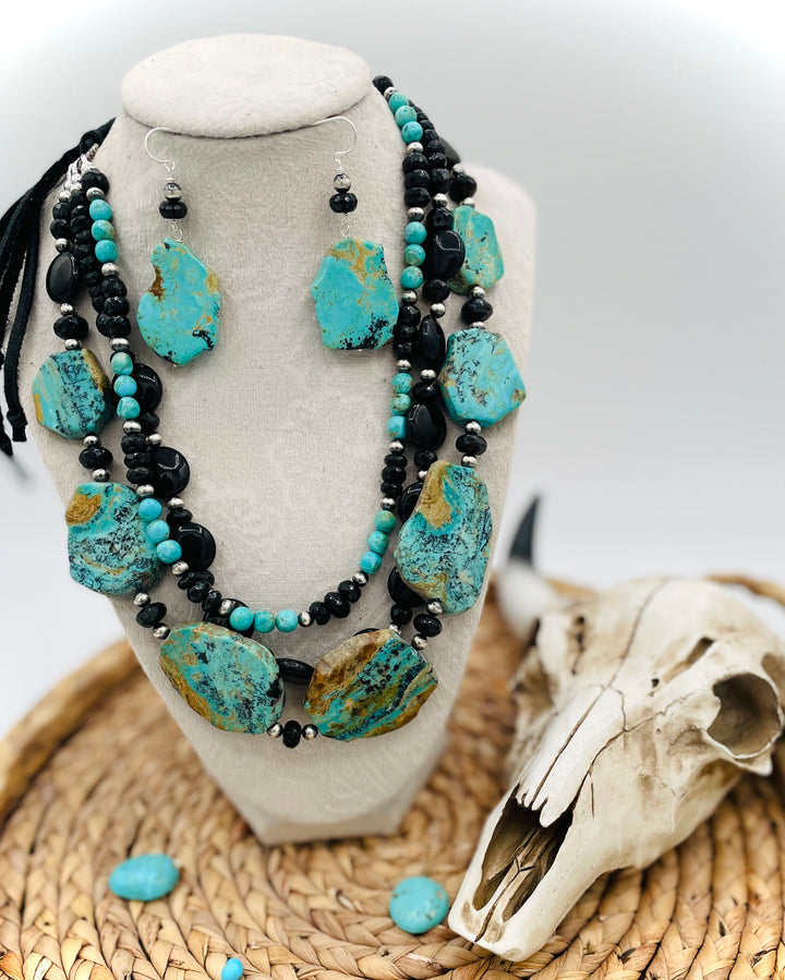 Beaded three strand necklace featuring Kingman turquoise, onyx, spinel, sterling silver, and finished with deer lace and slide bead. Includes matching earrings. Available only from Rockstar Cowgirl online or in store in Cody, Wyoming.