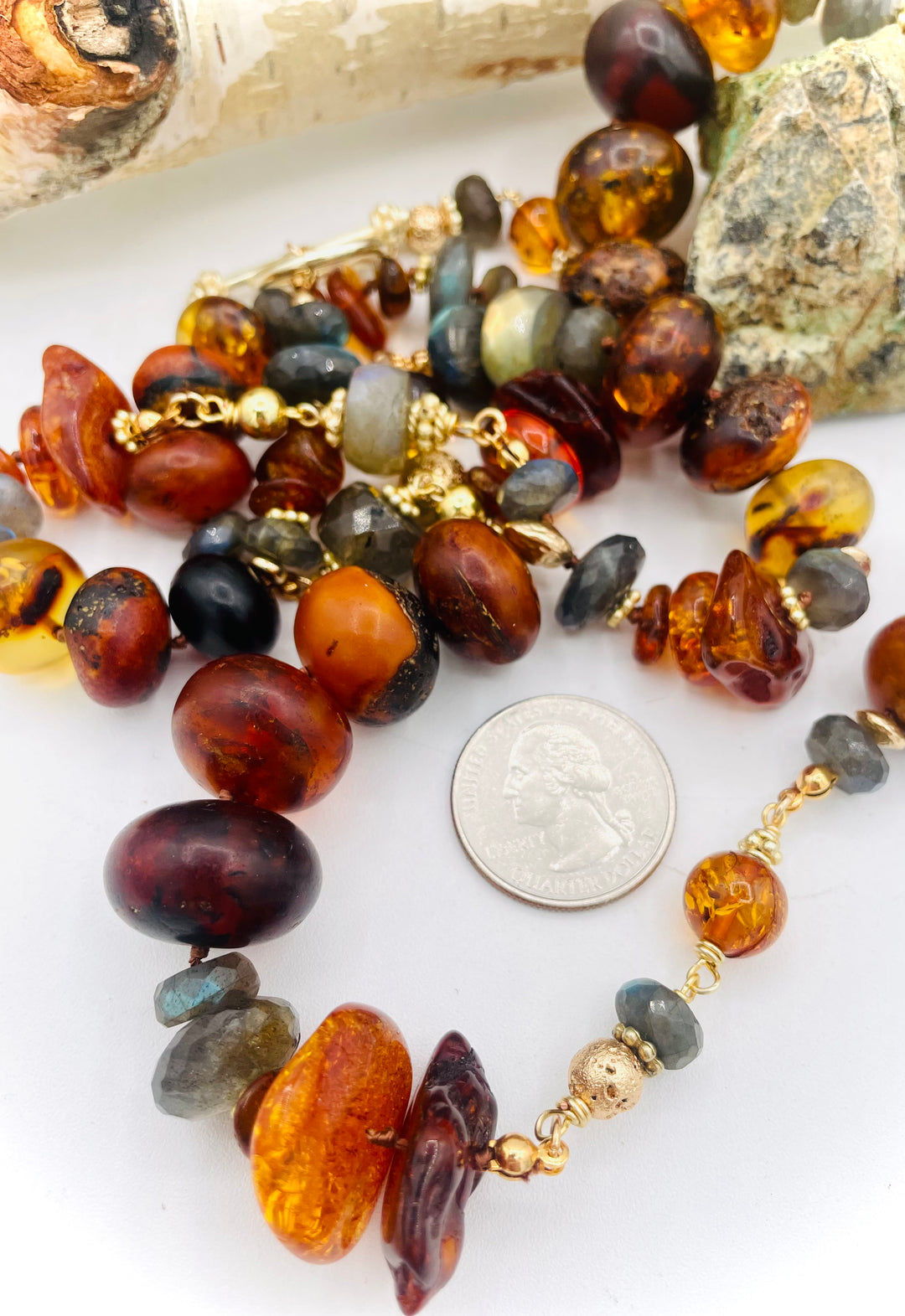 Silk knotted and wire wrapped treasure necklace featuring Baltic amber, labradorite, lava beads, and 14k gold accents. U.S. quarter for size reference. Available only from Rockstar Cowgirl online or in store in Cody, Wyoming. 
