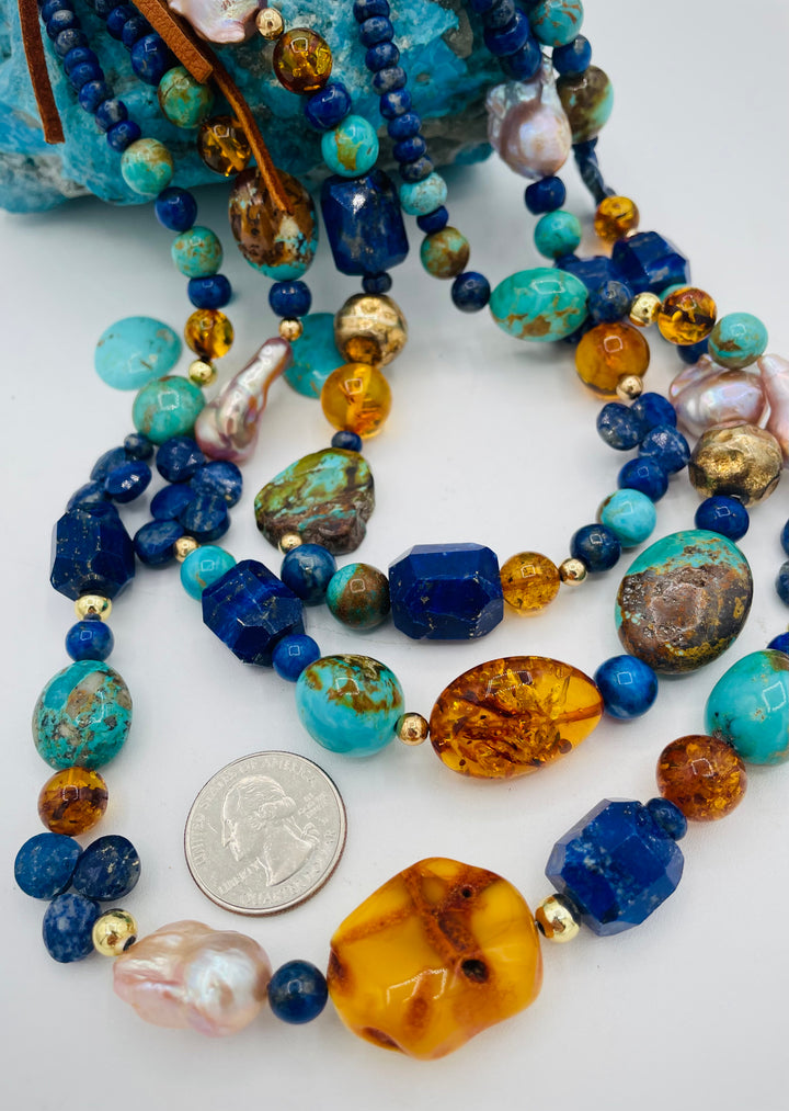 Beaded 3 strand necklace featuring lapis, Baltic amber, Kingman turquoise, 14K gold beads, natural luster pearls, and finished with deer lace in the back. U.S. quarter for size reference. Available only form Rockstar Cowgirl online or in store in Cody, Wyoming.