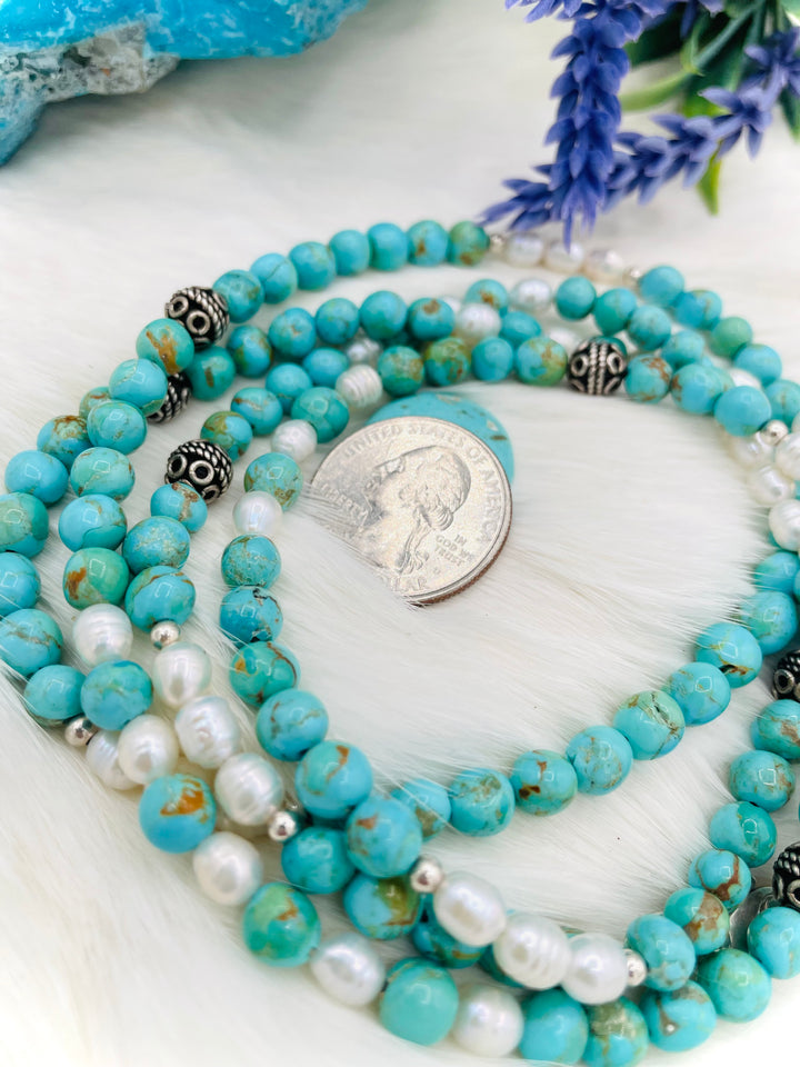 Beaded invention necklace featuring Kingman turquoise, freshwater pearls, sterling sliver accent beads, with sterling silver swivel lobsters, eye glasses loops, and cell phone case attachment bracket. U.S. quarter for size reference. Available only from Rockstar Cowgirl online or in store in Cody, Wyoming. 