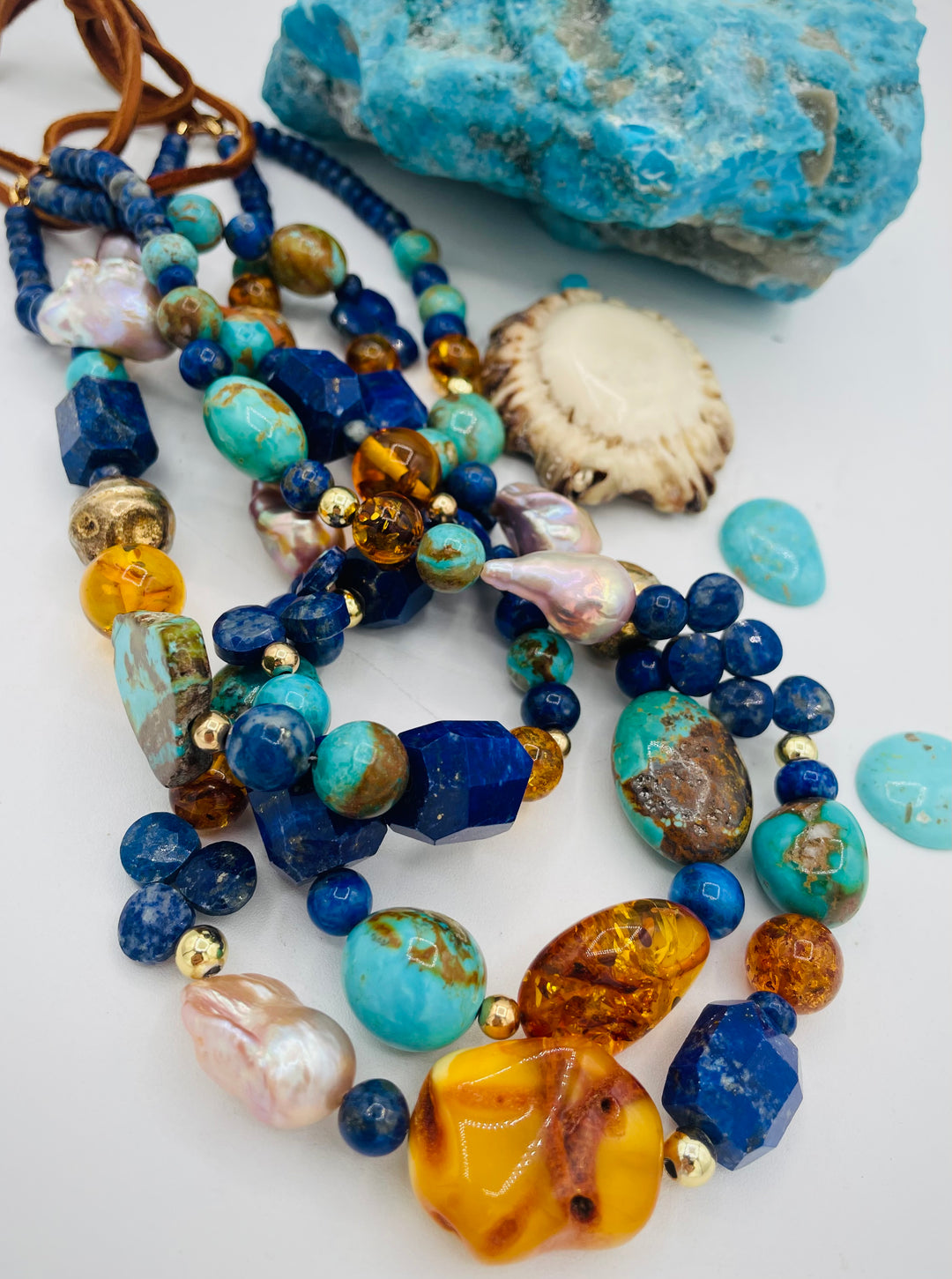 Beaded 3 strand necklace featuring lapis, Baltic amber, Kingman turquoise, 14K gold beads, natural luster pearls, and finished with deer lace in the back. Available only form Rockstar Cowgirl online or in store in Cody, Wyoming.