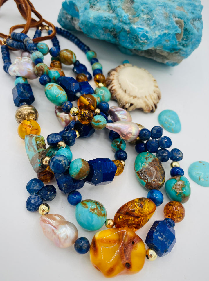 Beaded 3 strand necklace featuring lapis, Baltic amber, Kingman turquoise, 14K gold beads, natural luster pearls, and finished with deer lace in the back. Available only form Rockstar Cowgirl online or in store in Cody, Wyoming.