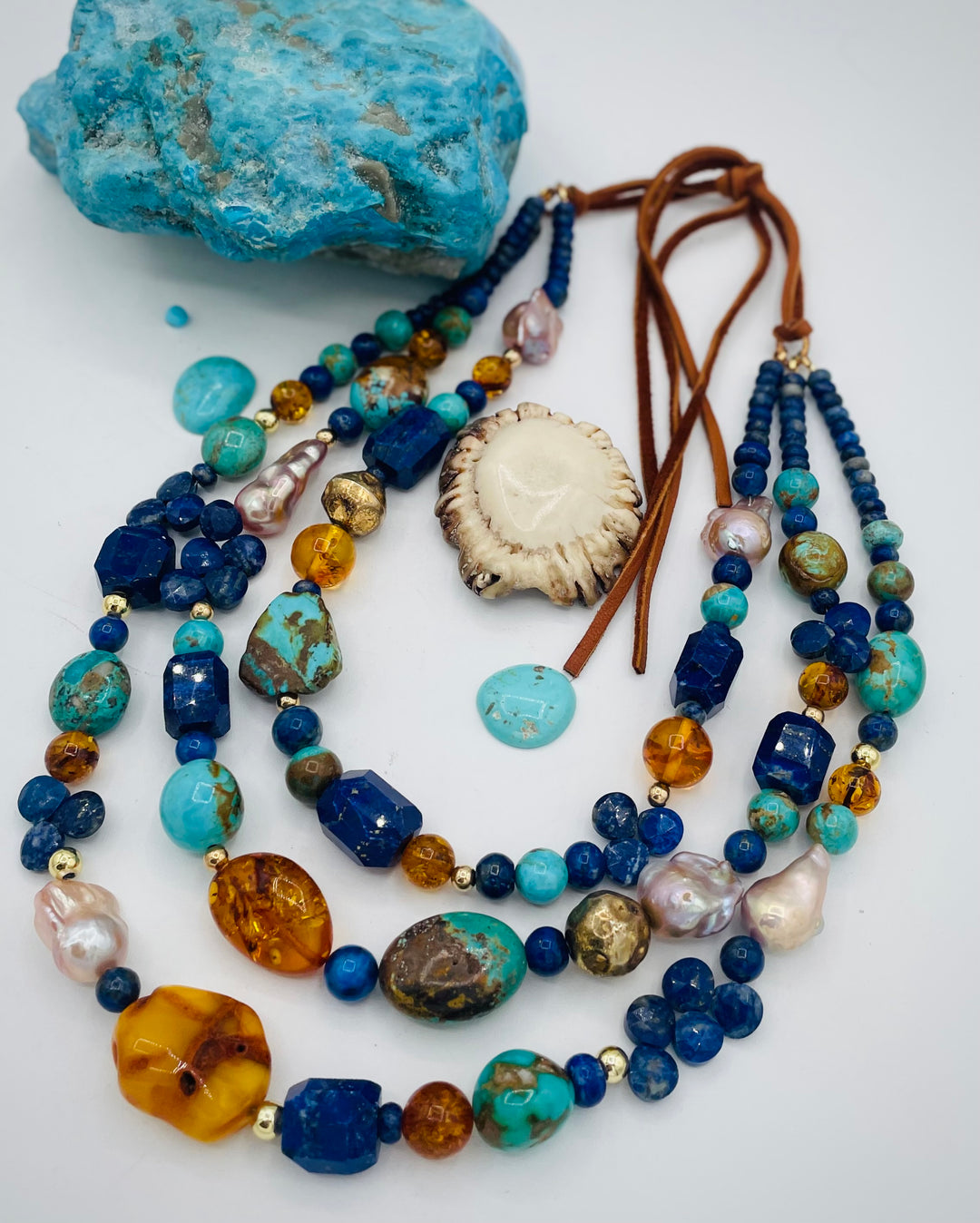 Beaded 3 strand necklace featuring lapis, Baltic amber, Kingman turquoise, 14K gold beads, natural luster pearls, and finished with deer lace in the back. Available only form Rockstar Cowgirl online or in store in Cody, Wyoming.