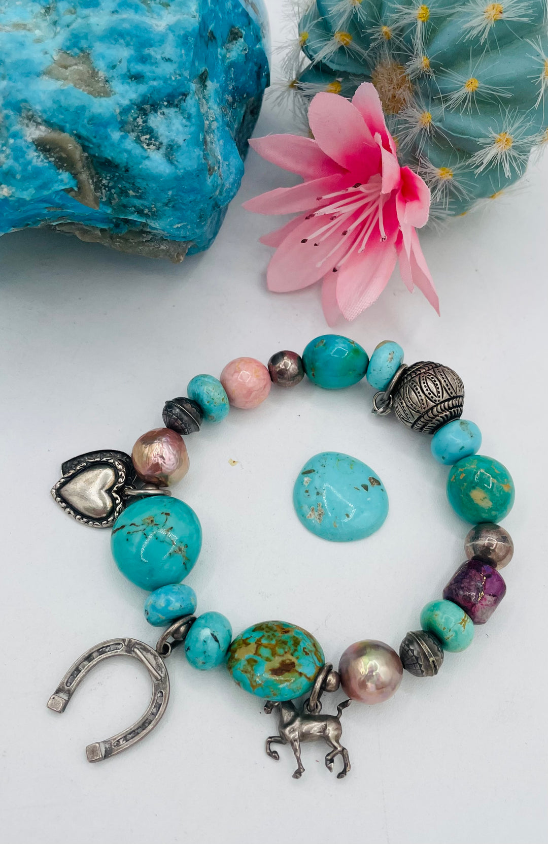 Beaded stretch bracelet featuring Kingman turquoise, royal beauty turquoise, pearls, rhodochrosite, purple turquoise, sterling silver beads and vintage sterling silver charms. Available only from Rockstar Cowgirl online or in store in Cody, Wyoming.