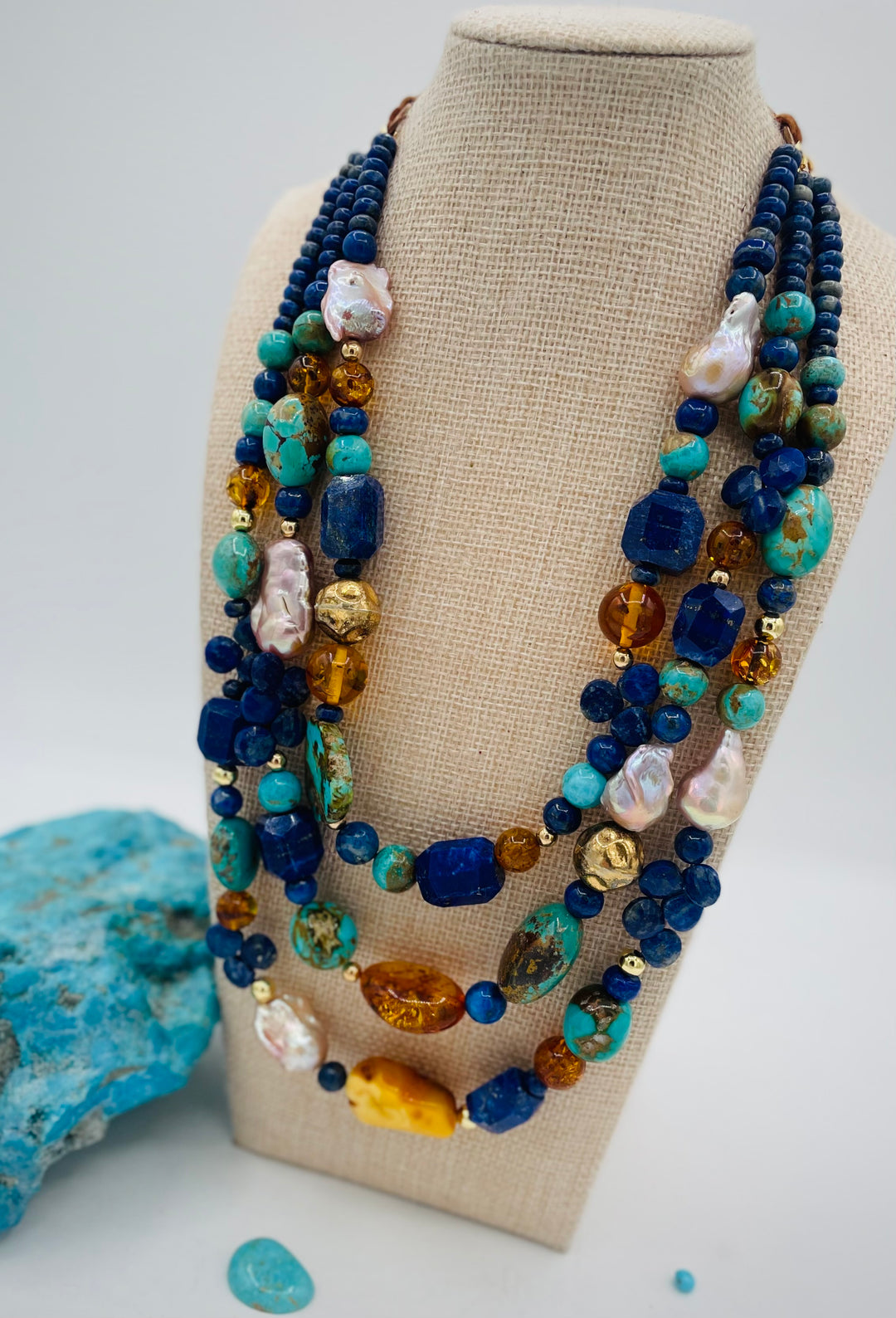 Beaded 3 strand necklace featuring lapis, Baltic amber, Kingman turquoise, 14K gold beads, natural luster pearls, and finished with deer lace in the back. Available only form Rockstar Cowgirl online or in store in Cody, Wyoming.
