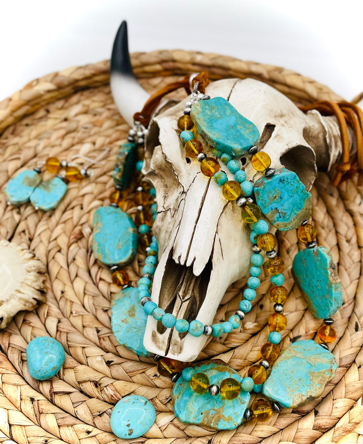 Beaded three strand necklace featuring Kingman turquoise, Baltic amber, sterling silver beads, and finished with deer lace and slide bead. Includes matching earrings. Available only from Rockstar Cowgirl online or in store in Cody, Wyoming.