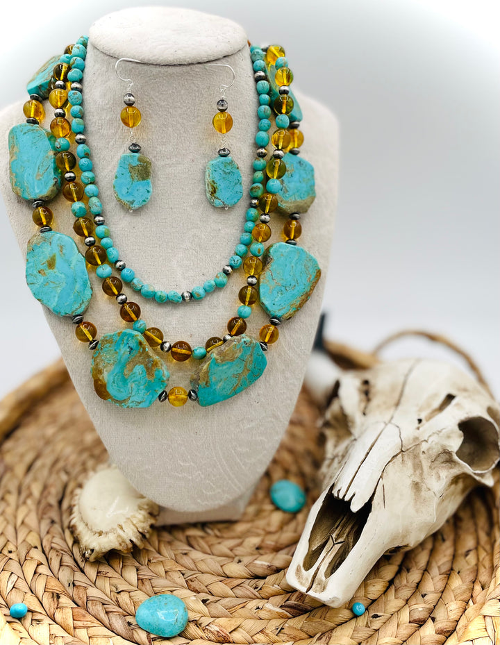 Beaded three strand necklace featuring Kingman turquoise, Baltic amber, sterling silver beads, and finished with deer lace and slide bead. Includes matching earrings. Available only from Rockstar Cowgirl online or in store in Cody, Wyoming.