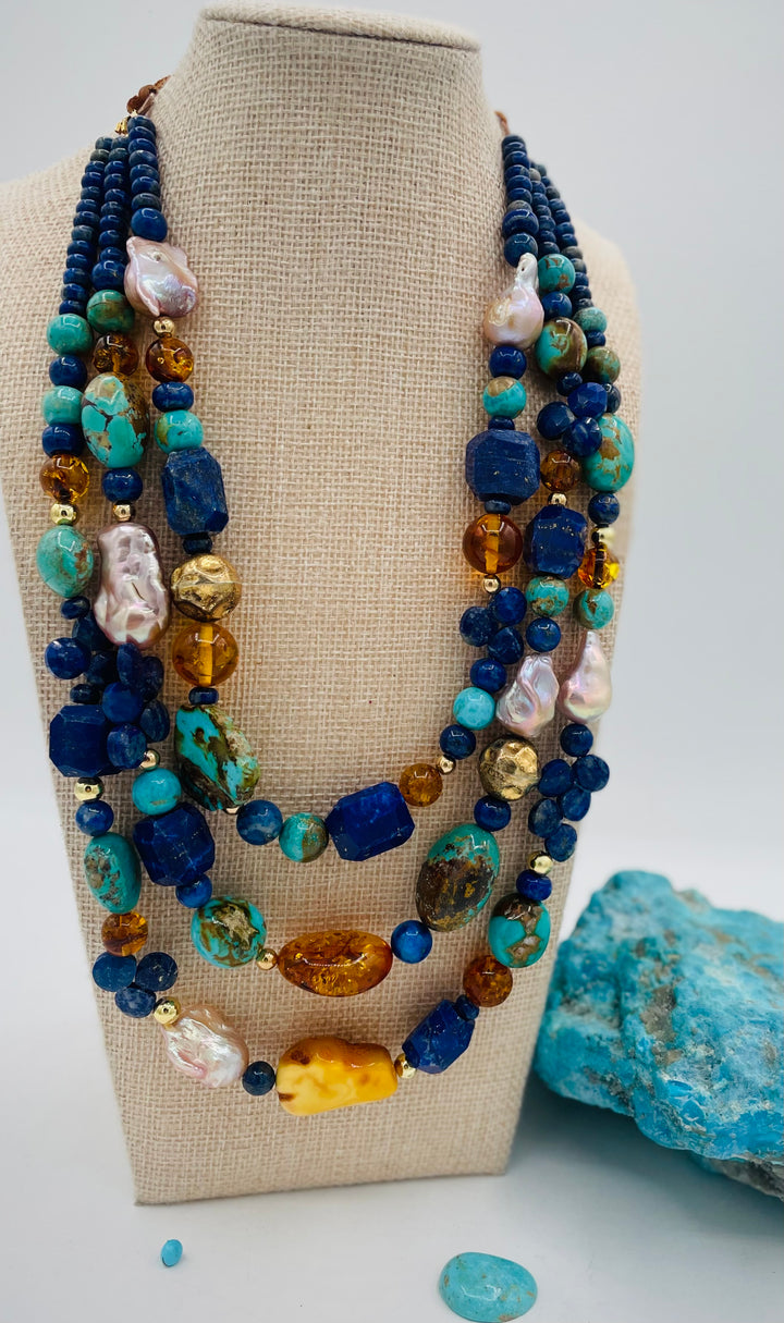 Beaded 3 strand necklace featuring lapis, Baltic amber, Kingman turquoise, 14K gold beads, natural luster pearls, and finished with deer lace in the back. Available only form Rockstar Cowgirl online or in store in Cody, Wyoming.