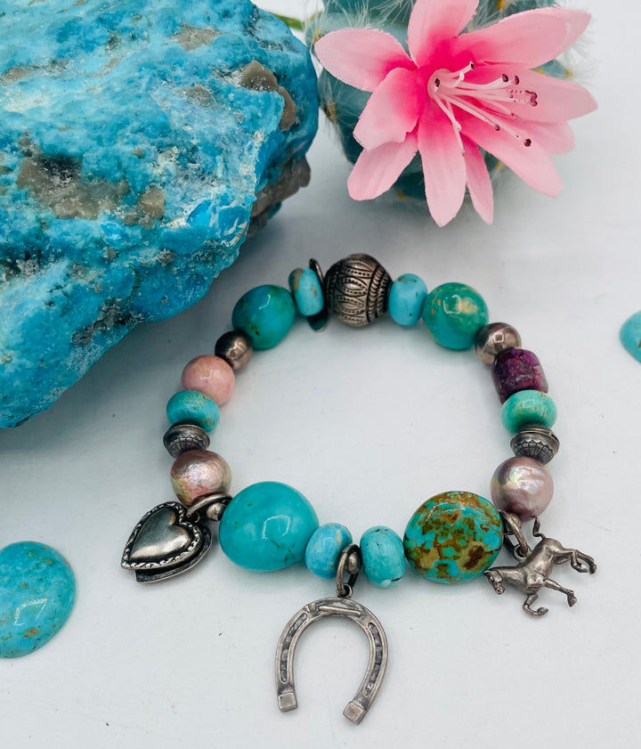 Beaded stretch bracelet featuring Kingman turquoise, royal beauty turquoise, pearls, rhodochrosite, purple turquoise, sterling silver beads and vintage sterling silver charms. Available only from Rockstar Cowgirl online or in store in Cody, Wyoming.