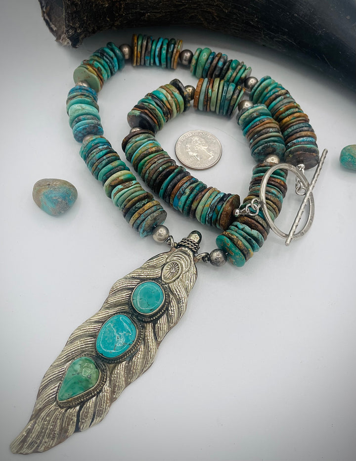 Handmade beaded necklace featuring turquoise discs, sterling silver beads, and Tibetan silver pendent with turquoise inlays. U.S. quarter for size reference. Available only from Rockstar Cowgirl online or in store in Cody, Wyoming.