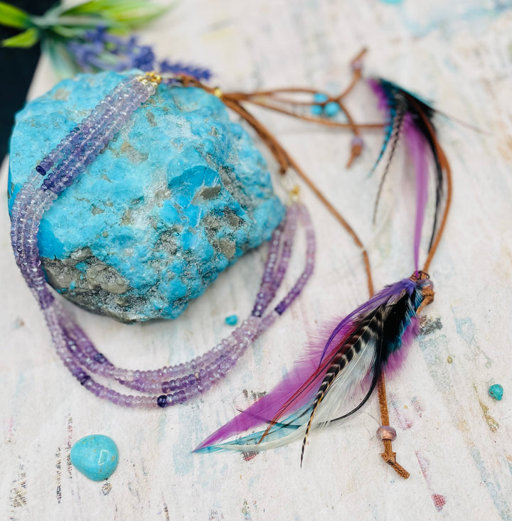 3 strand hatband or necklace of shaded amethyst with gold accents and finished with feathers, leather lace and a slide bead for fit. Available only from Rockstar Cowgirl online or in store in Cody, Wyoming.